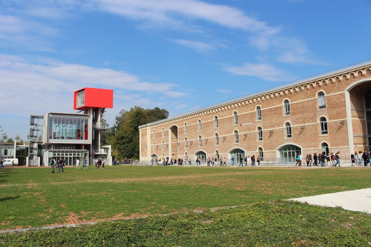 A panoramic view of the UPJV Citadelle campus in Amiens, showing its modern university buildings integrated within the historic citadel walls, surrounded by green spaces and walkways.